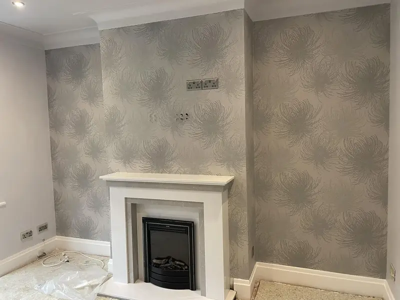Living room with grey botanical wallpaper on the chimney breast and alcoves around a white fire surround