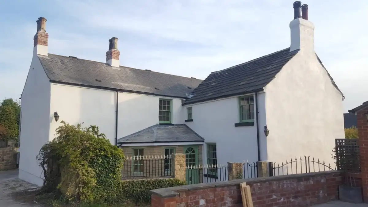 Farmhouse with white painted rendered walls and green windows, decorated by M.A Barton